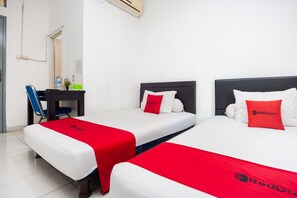 A hotel room with two beds, each with a white mattress and red bedspread. There is a desk with a chair and a water bottle on it. - RedDoorz Syariah near Grand Galaxy Park (Bekasi)