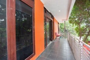 A covered balcony with a tiled floor, large windows, and a railing. - RedDoorz Syariah near Grand Galaxy Park (Bekasi)