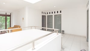 Quarto de hotel moderno com uma cama grande, uma varanda com grade de metal e vista para o exterior.