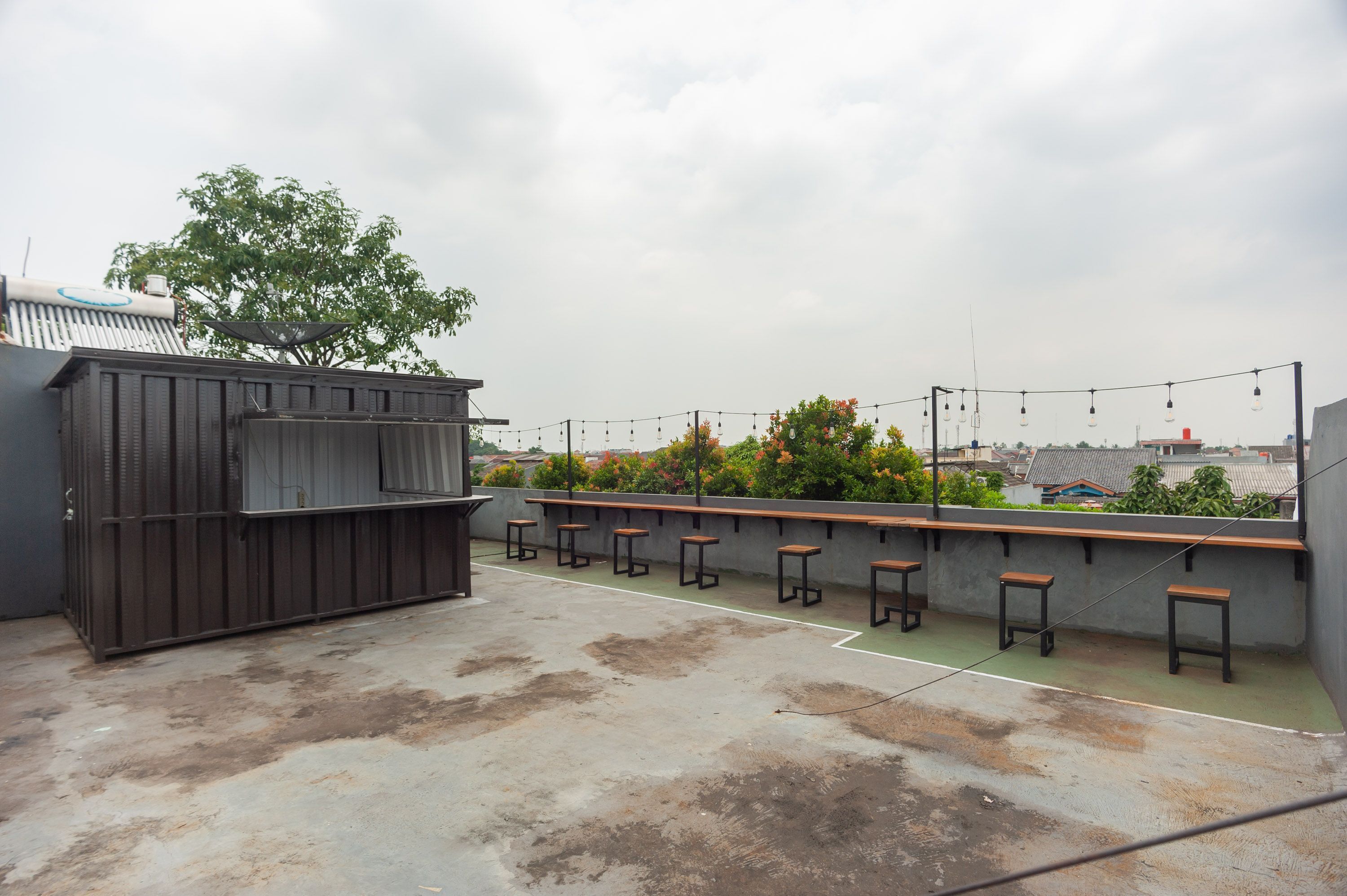 Terraza en la azotea con una parrilla, zona de estar y luces colgantes.