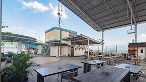 Un espace extérieur aménagé avec des tables et des chaises, un coin salon abrité et une vue sur le paysage urbain.
