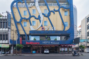 Un edificio con una fachada azul y beige distintiva, que presenta un letrero prominente de 'ovia' y un letrero de 'RedDoorz HEFU Restaurant' debajo.