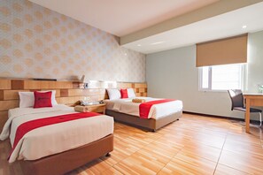 Habitación de hotel con dos camas, un escritorio y una ventana con vistas.