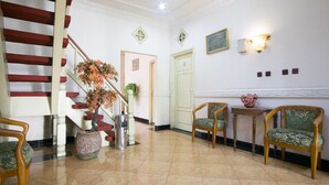 Un hall d’entrée avec un escalier, un comptoir d’accueil et deux chaises.