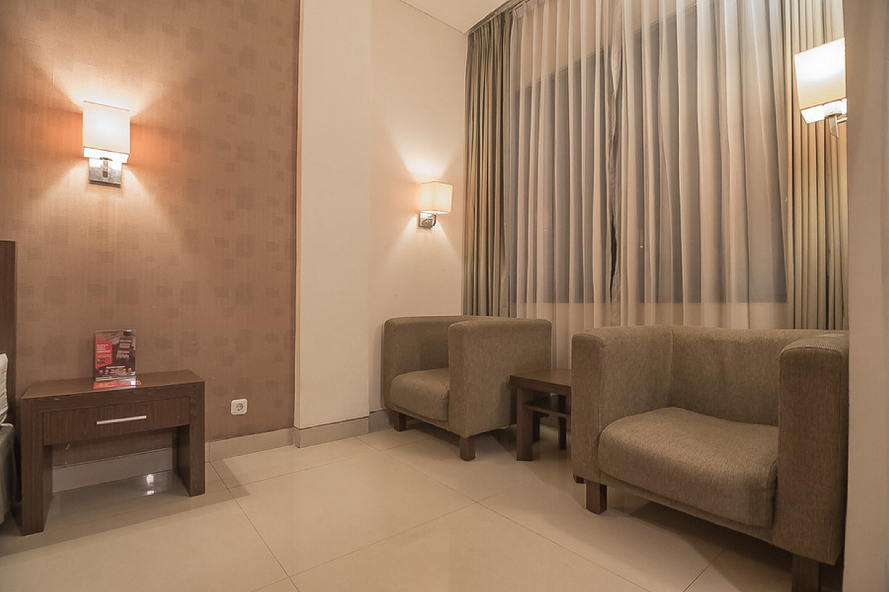 A hotel room with a sofa, a small table, and a lamp.