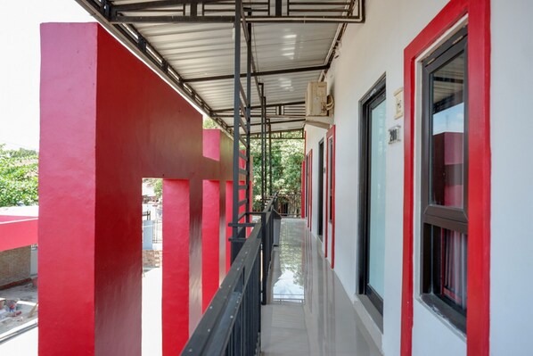 A corridor with red and white walls, a metal roof, and a window on the right. - RedDoorz Syariah near Alun Alun Tegal (Tegal)