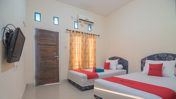 Une chambre d’hôtel avec deux lits, un téléviseur, un appareil de climatisation et une porte.