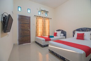 Ein Hotelzimmer mit zwei Betten, einem Fernseher, einer Klimaanlage und einer Tür.