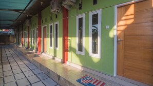 Un bâtiment à la façade verdoyante, doté de plusieurs portes et dont le sol est recouvert de carreaux.