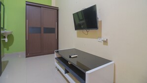 Une pièce avec un téléviseur fixé au mur, une armoire en bois et un lavabo.