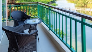 A balcony with wicker furniture and a view of a river. - Regenta Place Mandrem Beach-Resort (Mandrem)