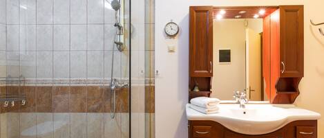 A bathroom with a shower, sink, and wooden cabinets.
