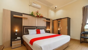 Een hotelkamer met een groot bed, een nachtkastje met een telefoon, een garderobe en een klein bureau met een lamp.