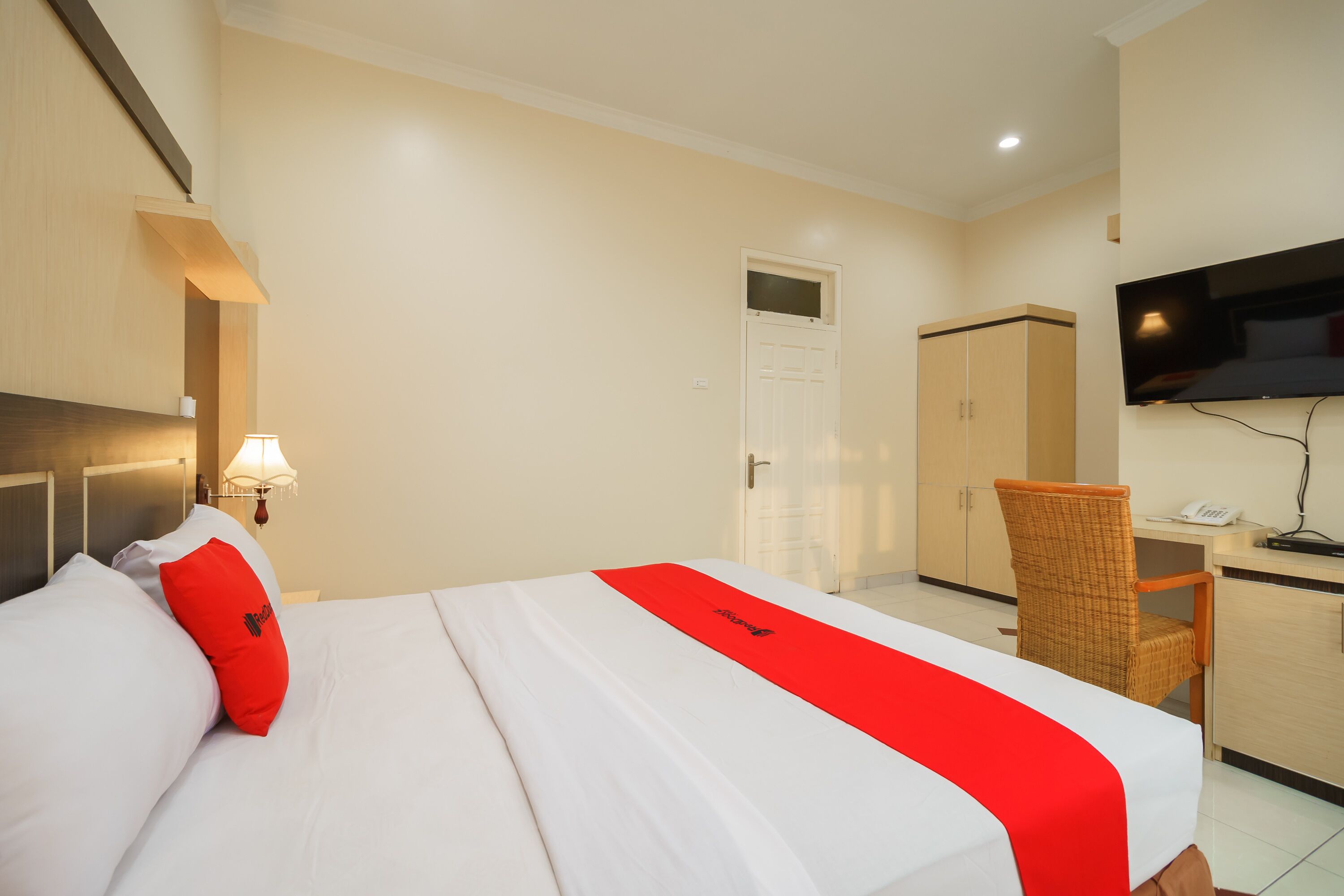 Habitación de hotel con cama, escritorio, silla, armario y televisor.