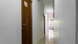 A hallway with a wooden door labeled "A4" and a tiled floor. - RedDoorz @ Kebon Kacang (Jakarta)