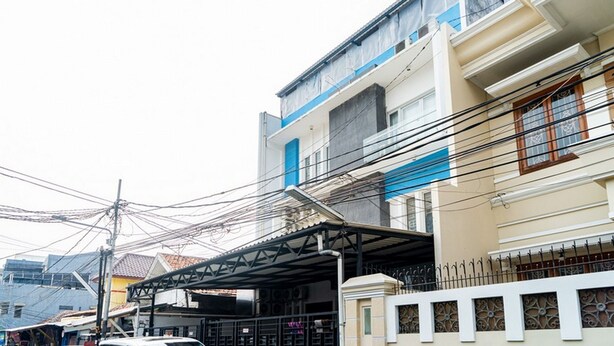 A multi-story residential building with a covered entrance and a balcony. - RedDoorz @ Kebon Kacang (Jakarta)