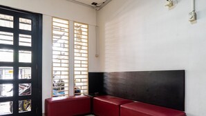 A room with a black and white wall, a red bench, and a door with windows. - RedDoorz @ Kebon Kacang (Jakarta)