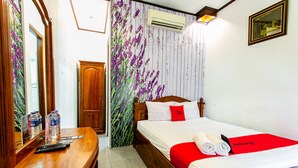 Habitación de hotel con una cama de madera, un escritorio con espejo y un papel tapiz floral.