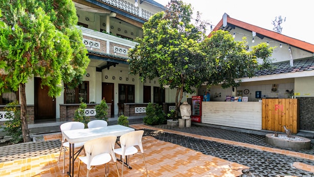 Un patio con piso de baldosas, una mesa con sillas y una valla de madera.