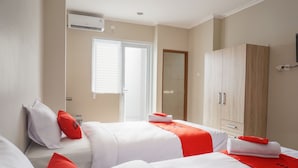 A hotel room with two beds, a wardrobe, a window, and an air conditioning unit. - Residences by RedDoorz near MT Haryono (Jakarta)