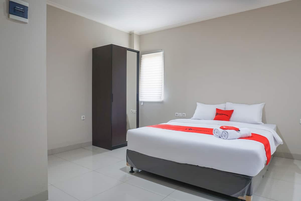 A hotel room with a bed, a wardrobe, and a window with blinds.
