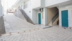 A building with a staircase leading to an upper floor, a covered outdoor area with hexagonal tiles, and a blue door. - Residences by RedDoorz near MT Haryono (Jakarta)