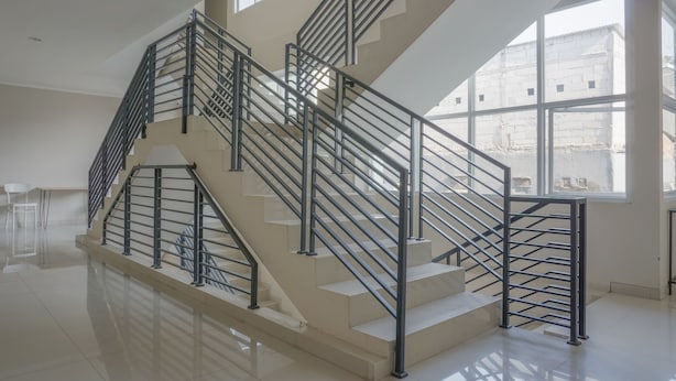 A modern interior with a multi-level staircase, large windows, and a clean, reflective floor. - Residences by RedDoorz near MT Haryono (Jakarta)