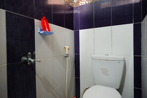 A bathroom with a toilet, a shower, and a towel rack. - RedDoorz Syariah near Menara Kudus (Kudus)