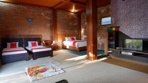 Une chambre avec deux lits, une télévision et un mur en briques.