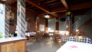 Un grand espace dédié à la salle à manger, avec des tables et des chaises en bois, un mur en briques et un escalier.