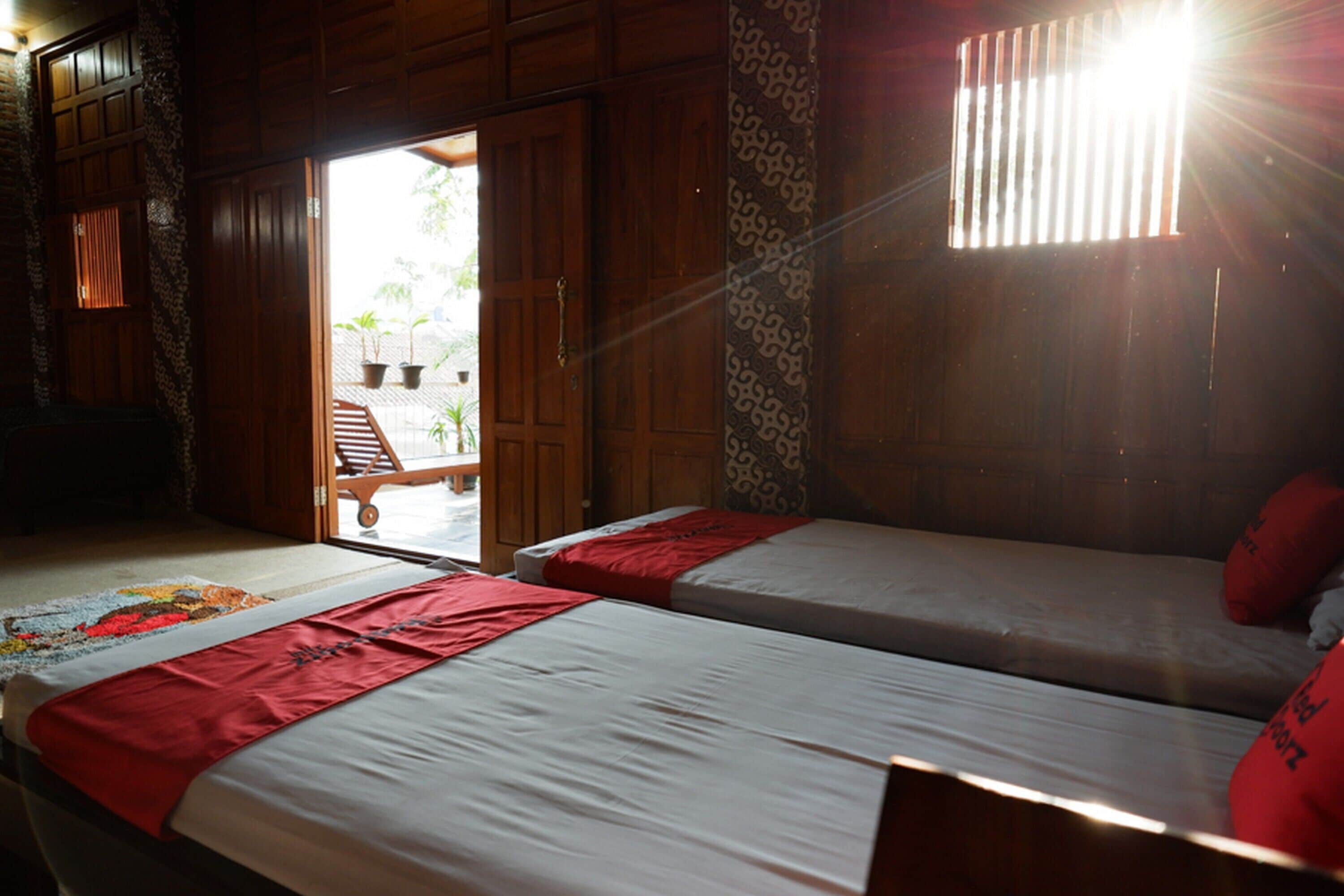 A room with two beds, wooden walls, and a view of the outside.