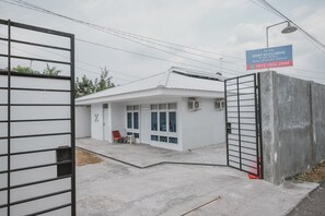 Propiedad residencial privada con reja, fachada blanca, un porche cubierto y un letrero azul.
