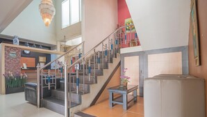 A spacious interior with a staircase, a reception desk, and a seating area.