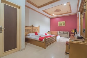 Un dormitorio con una cama de madera, un sofá color beige, una pared roja y un techo con diseño decorativo.