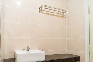 A bathroom with beige tiles, a white sink, and a black countertop.