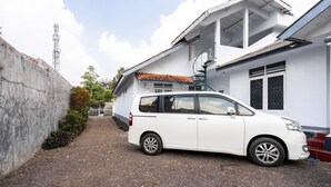 A white van parked in front of a white building with a tiled roof and a spiral staircase. - RedDoorz Syariah near RSUD Cimacan (Cipanas)