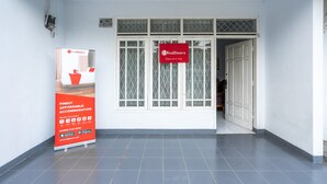 A hallway with a RedDoorz sign, a large poster, and a tiled floor. - RedDoorz Syariah near RSUD Cimacan (Cipanas)