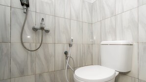 A bathroom with a toilet, a shower with a handheld showerhead, and a wall-mounted faucet. - RedDoorz Syariah near RSUD Cimacan (Cipanas)