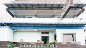 A hotel with a two-story structure, a covered entrance, and potted plants in front. - RedDoorz near Mikie Holiday Funland Berastagi (Berastagi)