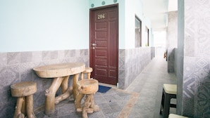 A hallway with a wooden bench, a brown door with the number 206, and patterned walls. - RedDoorz near Mikie Holiday Funland Berastagi (Berastagi)