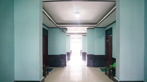 A hallway with a tiled floor and light blue walls, leading to a bright room at the end. - RedDoorz near Mikie Holiday Funland Berastagi (Berastagi)