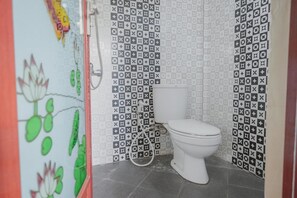 Un baño con inodoro, ducha y una pared con diseño geométrico.