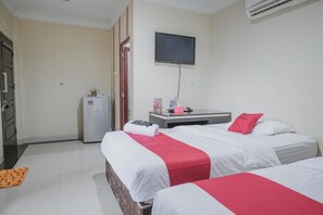 Habitación de hotel con dos camas, un televisor montado en la pared, un escritorio pequeño con una silla y un refrigerador.