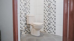 Un ba ño pequeño y cerrado con inodoro, lavamanos y paredes de azulejos.