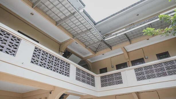 Un interior de varios niveles con una escalera central, balcones con barandillas decorativas y un tragaluz.