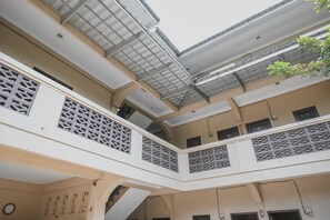 Un interior de varios niveles con una escalera central, balcones con barandillas decorativas y un tragaluz.