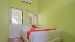 A bedroom with a bed, a door, and a window. - RedDoorz Syariah near Museum Wisma Karya Subang (Subang)