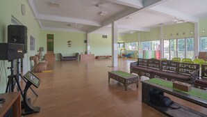 A spacious room with a wooden floor, a large window, and a seating area with a bench and chairs. - RedDoorz Syariah near Museum Wisma Karya Subang (Subang)
