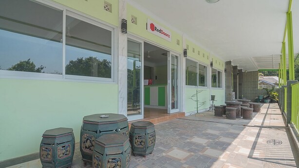 A RedDoorz store with a covered outdoor area featuring hexagonal stools and potted plants. - RedDoorz Syariah near Museum Wisma Karya Subang (Subang)