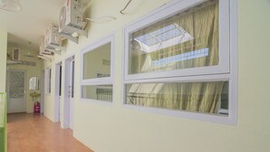 A hallway with multiple windows, a tiled floor, and ceiling fans. - RedDoorz Syariah near Museum Wisma Karya Subang (Subang)